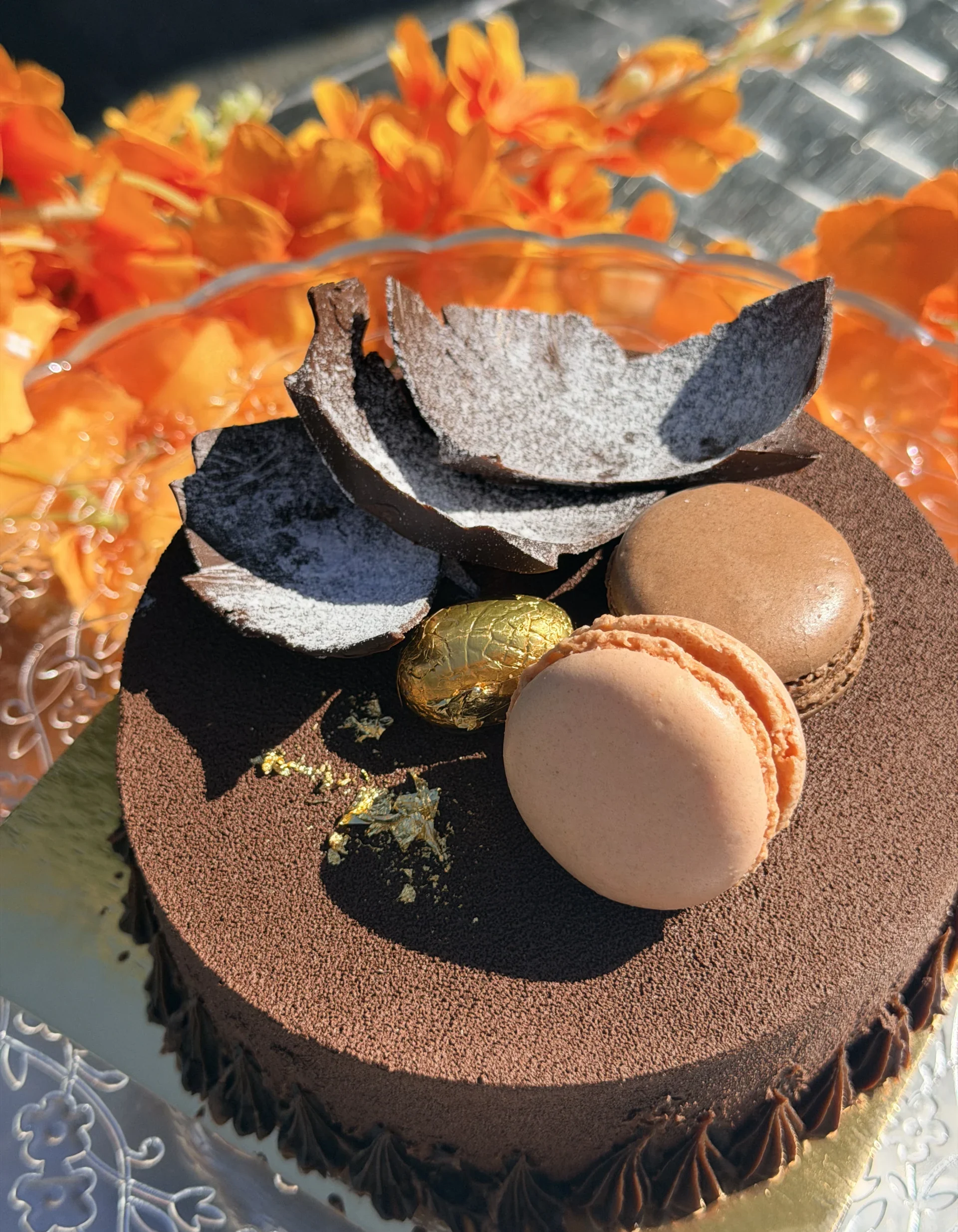 Entremets chocolat artisanal décoré de macarons, feuilles de chocolat et feuilles d'or, gâteau sur mesure halal réalisé à La manufacture du goût, Champigny-sur-Marne (94)