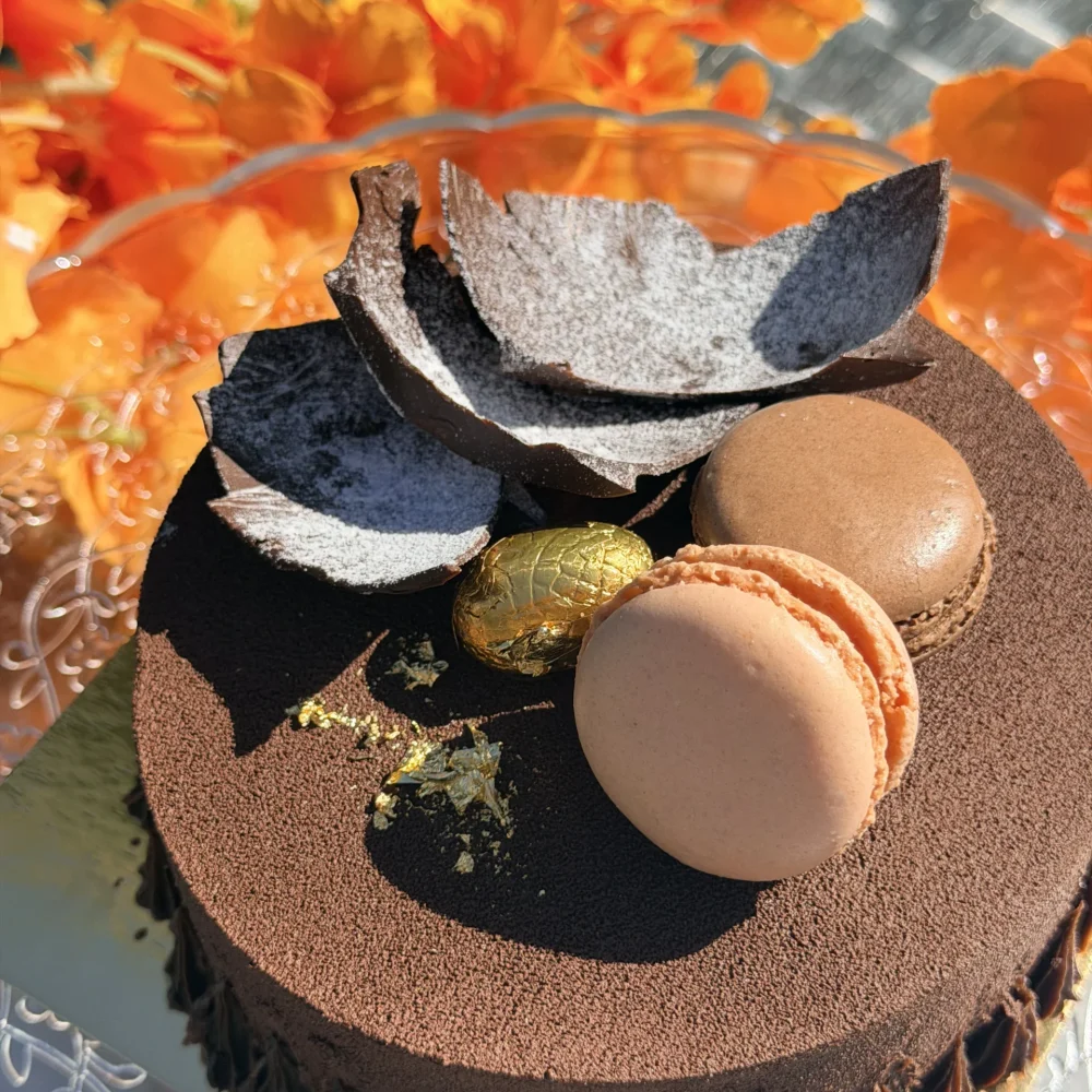 Entremets chocolat artisanal décoré de macarons, feuilles de chocolat et feuilles d'or, gâteau sur mesure halal réalisé à La manufacture du goût, Champigny-sur-Marne (94)